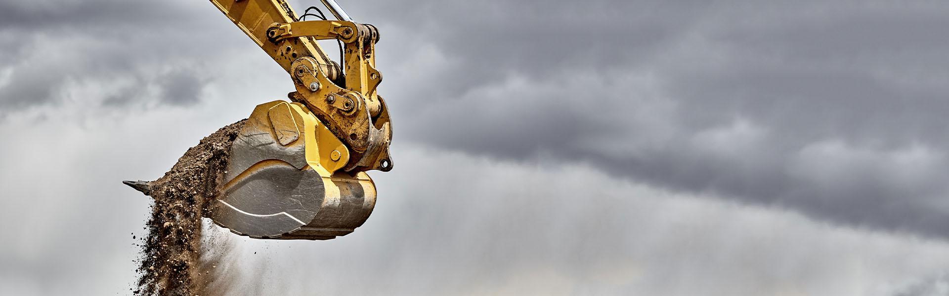 Slajd #1 - wysypująca się ziemia z łopaty koparki