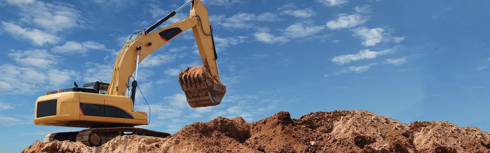 Slajd #2 - żółta koparka z łopatą pełną ziemi